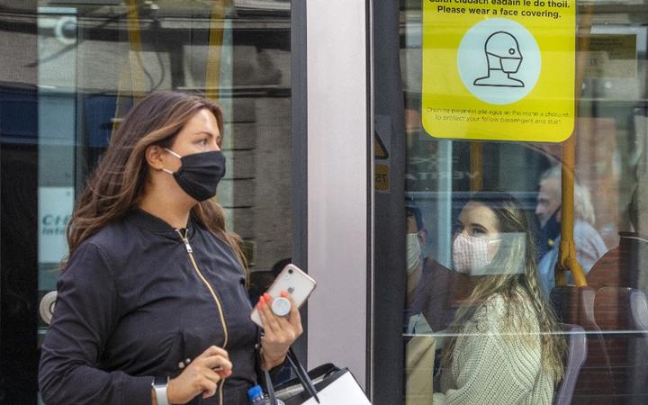 A woman wearing a face mask or covering due to the COVID-19 pandemic, exits a tram in Dublin on September 18, 2020, 