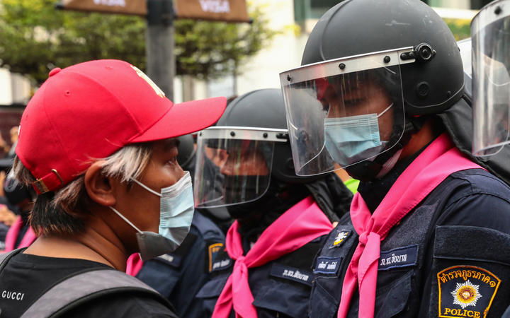 A pro-democracy protester faces off against a police officer in Bangkok on 15 October 2020, after the Thai government banned demonstrations.