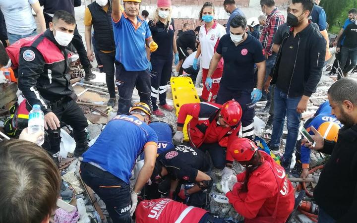 Rescuers search for survivors at a collapsed building after a powerful earthquake struck Turkey's western coast and parts of Greece, in Izmir, on October 30, 2020. 