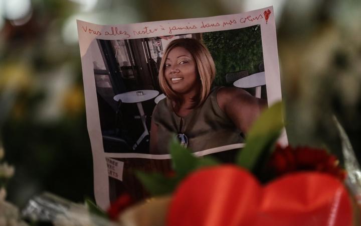 The portrait of a victim is displayed among candles and flowers on the doorsteps of the Notre-Dame de l'Assomption Basilica in Nice on October 30, 2020, a day after a knife attacker killed three people