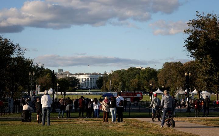 WASHINGTON, DC - OCTOBER 02: Bystanders look on as Marine One, the presidential helicopter, waits on the south lawn at the White House to carry U.S. President Donald Trump to Walter Reed National Military Medical Center October 2, 2020 in Washington, DC. 