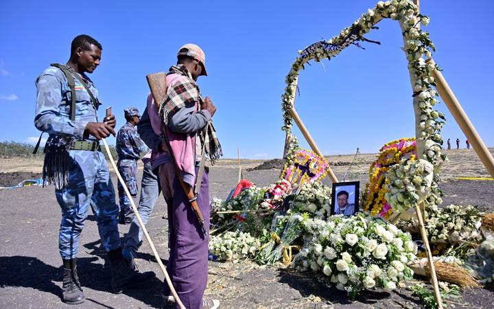 An ethiopian federal policeman and an Oromo tribesman look at a memorial to victims at the crash site of an Ethiopian airways operated Boeing 737 MAX aircraft on March 16, 2019 in Oromia region. - 