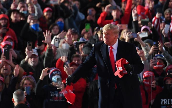 US President Donald Trump throws MAGA hats to supporters as he arrives for a rally at Pittsburgh-Butler Regional Airport in Butler, Pennsylvania on October 31, 2020. (Photo by MANDEL NGAN / AFP)