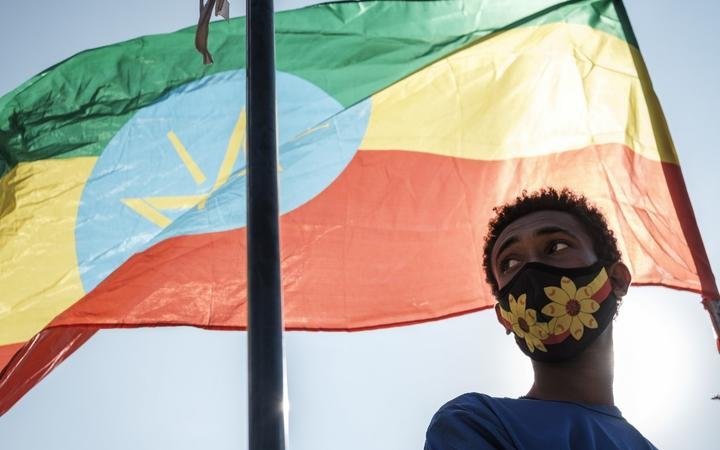 A youngster stands below an Ethiopian national flag during a blood donation rally organised by the city administration of Addis Ababa on 12 November, 2020.