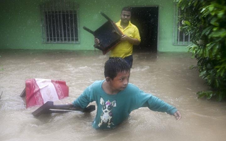 A boy and a man save chairs from a flooded house due to the heavy rains caused by Hurricane Eta, now degraded to a tropical storm, in Puerto Barrios, Izabal 310 km north Guatemala City on November 5, 2020. 