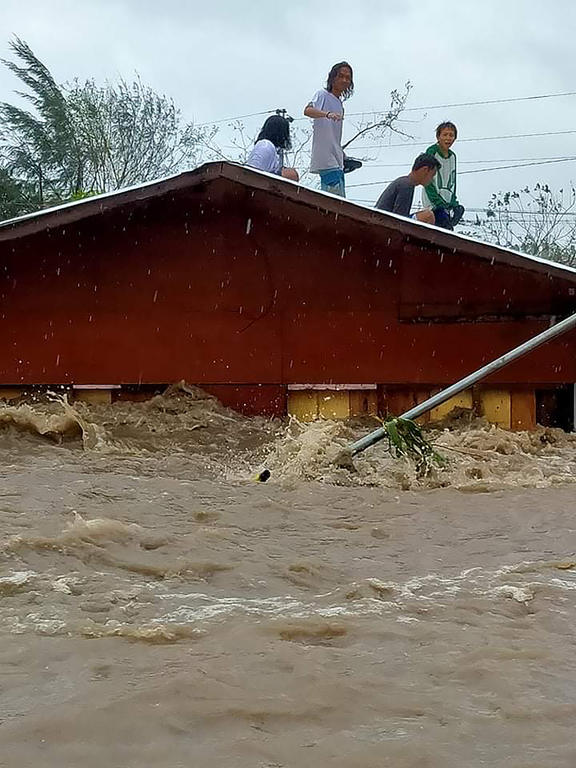 Residents stand on the roof of their house after a river overflowed in heavy rains brought byTyphoon Goni. Handout photo taken on 1 November 2020 from Alejandro Miraflor's Facebook page.