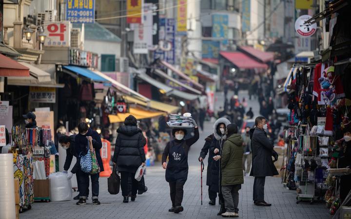 A restaurant worker carries a tray of food through Namdaemun market in Seoul on 11 December 2020. 