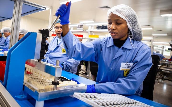 In this picture taken on December 21, 2020, employees work on the production line of a COVID-19 coronavirus home test unit at the production facility of Australian digital diagnostics company Ellume in Brisbane. 
