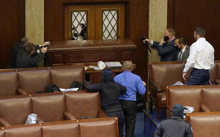 US Capitol police officers point their guns at a door that was vandalised in the House Chamber during a joint session of Congress on January 06, 2021 in Washington, DC. 