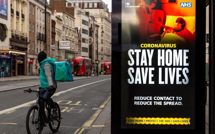 A delivery man on his bicycle is seen riding by the NHS 'Stay Home' poster as the UK's government introduced strict Coronavirus restrictions earlier this month due to sharp increase in numbers of Covid-19 cases in UK o)