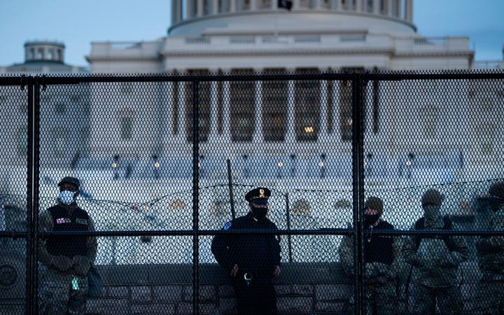 A Capitol Police officer stands with members of the National Guard behind a crowd control fence surrounding Capitol Hill a day after a pro-Trump mob broke into the US Capitol on January 7, 2021, in Washington, DC.