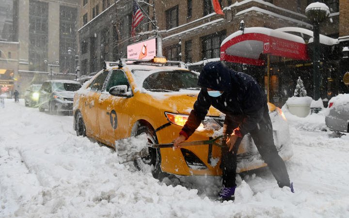A taxi cab driver shovels through heavy snow during a winter storm on 2 February, in New York City. 